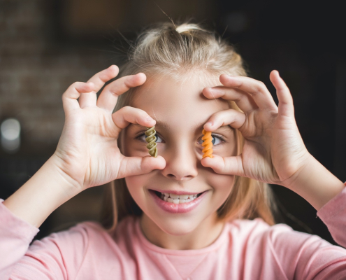 Meisje met macaroni in handen als symbool voor koolhydraten