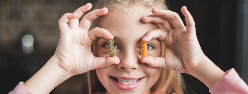 Meisje met macaroni in handen als symbool voor koolhydraten
